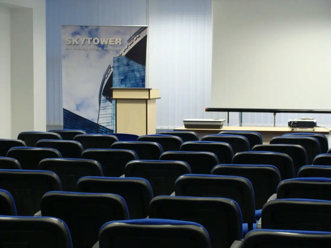 Sala de conferințe SKYTOWER, cu rânduri de scaune, tribună și ecran